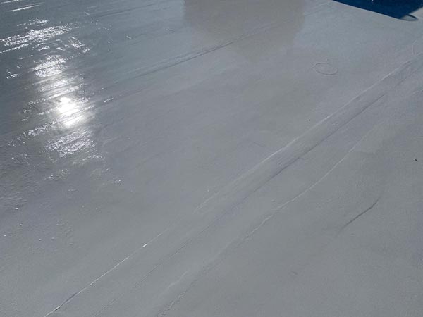 Close-up of a flat light-gray surface with sun glare and visible panel joints or seams, likely part of an aircraft wing or rooftop.